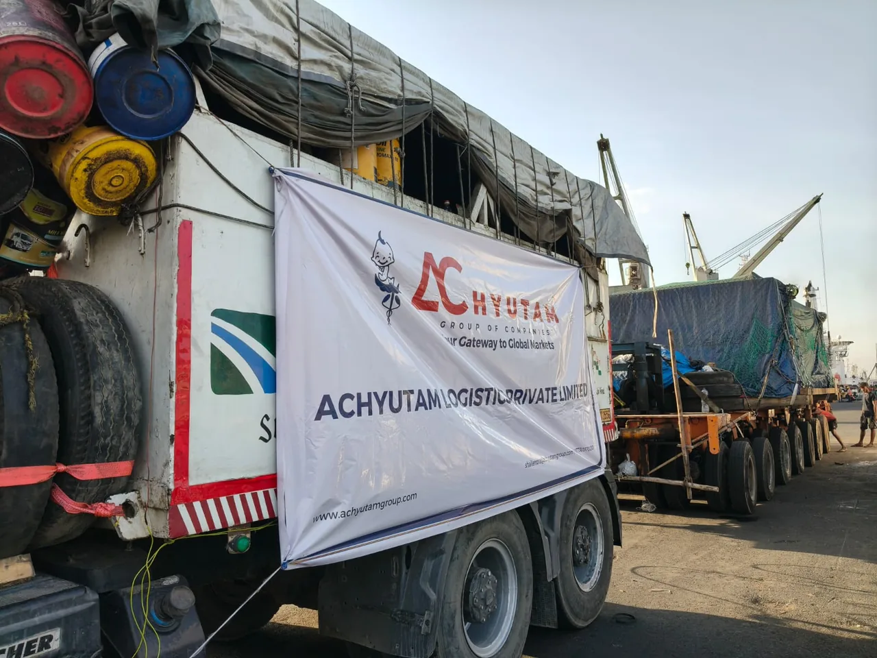 ACHYUTAM Logistics banner on a loaded truck at the port